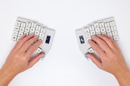 Two hands typing on the Mantaray Pro Wireless with a white background